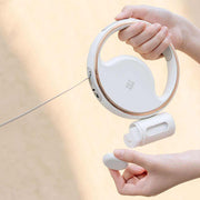 Automatic Lighting Retractable Dog Leash with LED night light, one-button retraction, and built-in garbage bag holder in white color.