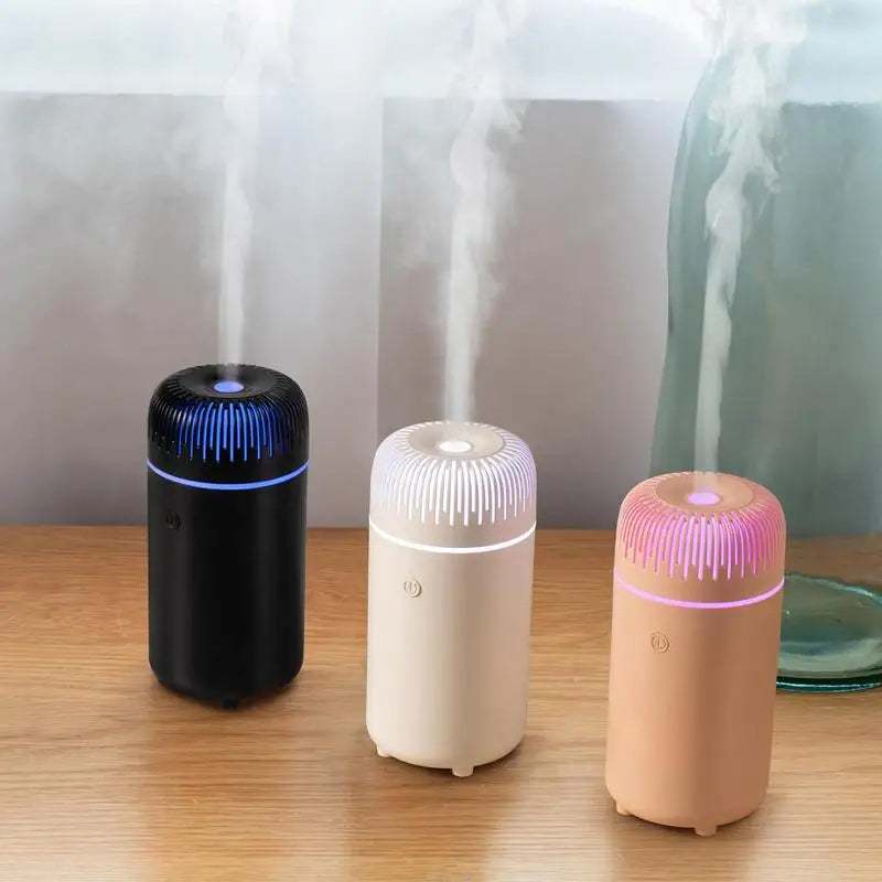 Natural Oil Car Air Diffuser in black, white, and pink with LED lights emitting mist on wooden surface