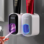 Wall mounted automatic toothpaste holder dispensing toothpaste onto toothbrush in modern bathroom