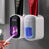 Wall mounted automatic toothpaste holder dispensing toothpaste onto toothbrush in modern bathroom